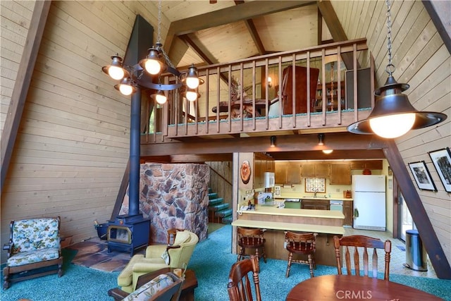 60027 Cascadel Dr S, North Fork, CA 93643 - carpeted living area featuring a wood stove, a sink, stairs, high vaulted ceiling, and wood walls