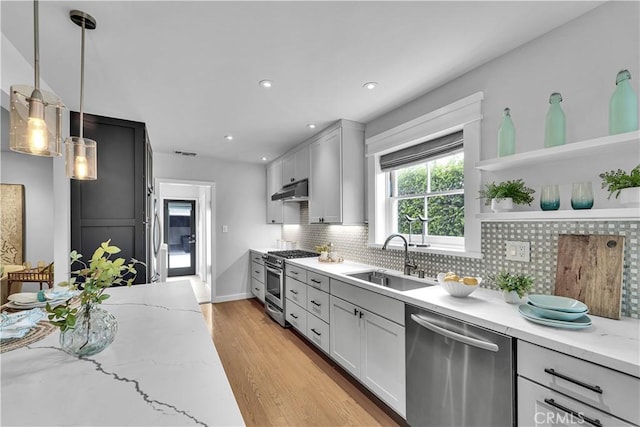 21820 Dumetz Rd, Woodland Hills, CA 91364 - kitchen with appliances with stainless steel finishes, a sink, under cabinet range hood, light stone countertops, and light wood-style flooring