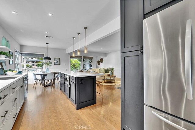 21820 Dumetz Rd, Woodland Hills, CA 91364 - kitchen featuring freestanding refrigerator, light wood-style flooring, light countertops, recessed lighting, and a kitchen bar