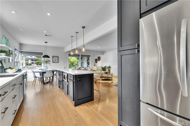 21820 Dumetz Rd, Woodland Hills, CA 91364 - kitchen featuring stainless steel fridge, light wood finished floors, light countertops, recessed lighting, and a breakfast bar