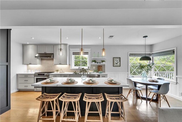 21820 Dumetz Rd, Woodland Hills, CA 91364 - kitchen with gas stove, gray cabinetry, under cabinet range hood, light countertops, and a wainscoted wall
