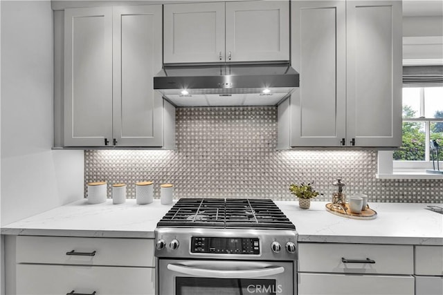 21820 Dumetz Rd, Woodland Hills, CA 91364 - kitchen with stainless steel gas stove, under cabinet range hood, tasteful backsplash, and light stone counters
