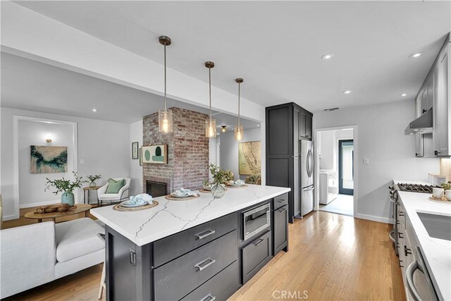 21820 Dumetz Rd, Woodland Hills, CA 91364 - kitchen with under cabinet range hood, appliances with stainless steel finishes, light stone counters, open floor plan, and recessed lighting