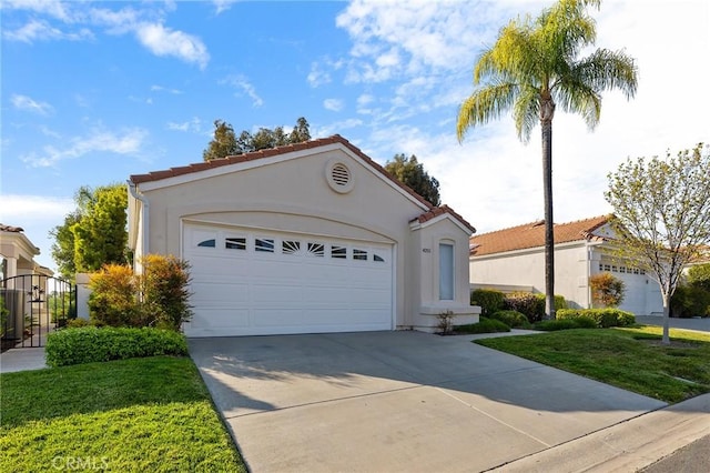 mediterranean / spanish-style house with a tile roof, a front yard, stucco siding, and driveway