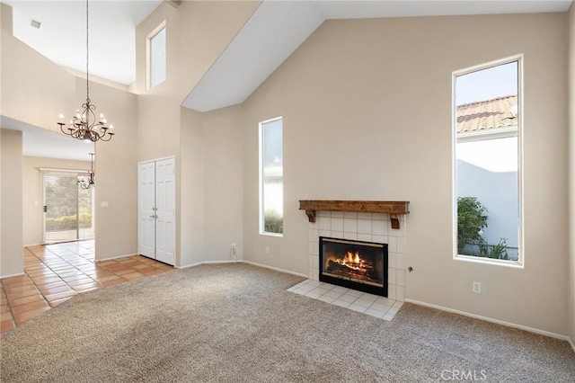 unfurnished living room featuring carpet flooring, a tile fireplace, high vaulted ceiling, a notable chandelier, and tile patterned flooring
