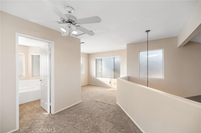 hall featuring carpet flooring and baseboards