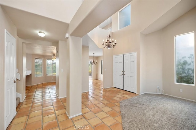 entrance foyer with light tile patterned flooring, a notable chandelier, and baseboards