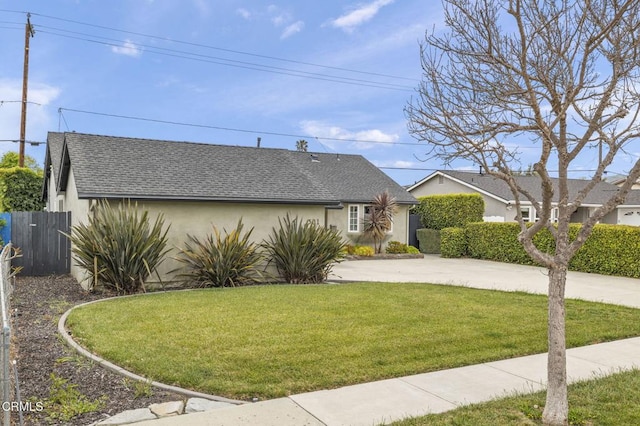 single story home featuring a front lawn, stucco siding, roof with shingles, and fence