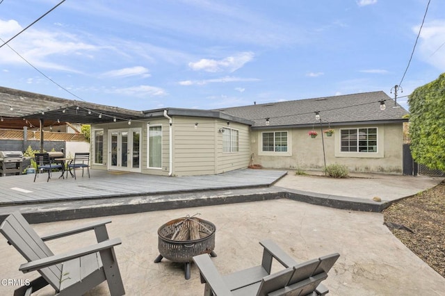 back of house featuring fence, a patio area, a deck, a fire pit, and french doors