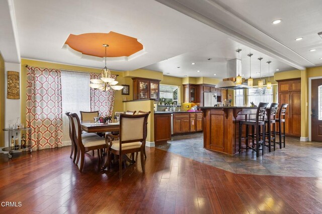 dining area featuring recessed lighting, baseboards, an inviting chandelier, dark wood-type flooring, and a raised ceiling