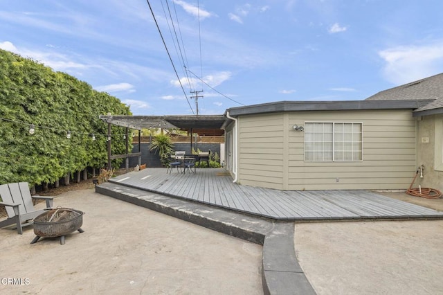 wooden deck with a fire pit, a patio, and fence