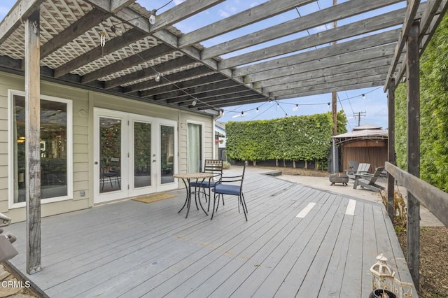 wooden deck with a hot tub, a pergola, and french doors