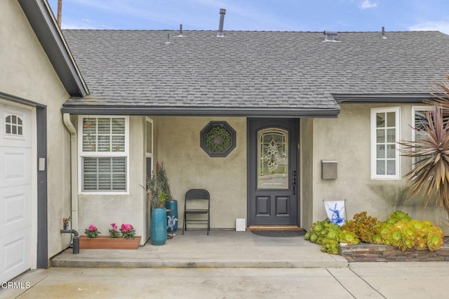 entrance to property featuring stucco siding and roof with shingles