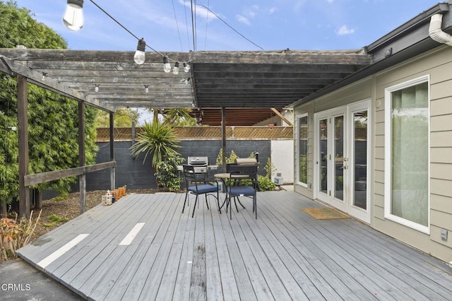 deck with a pergola, a fenced backyard, outdoor dining space, and french doors