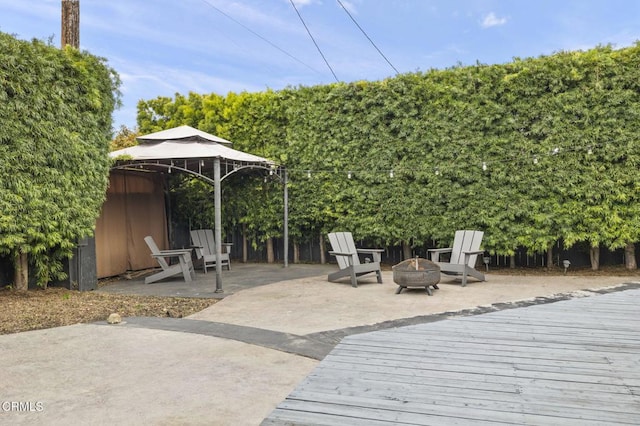 wooden deck with a gazebo, a patio area, and a fire pit
