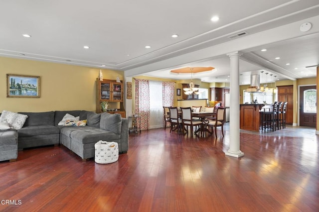 living room featuring recessed lighting, an inviting chandelier, visible vents, ornate columns, and dark wood-style floors