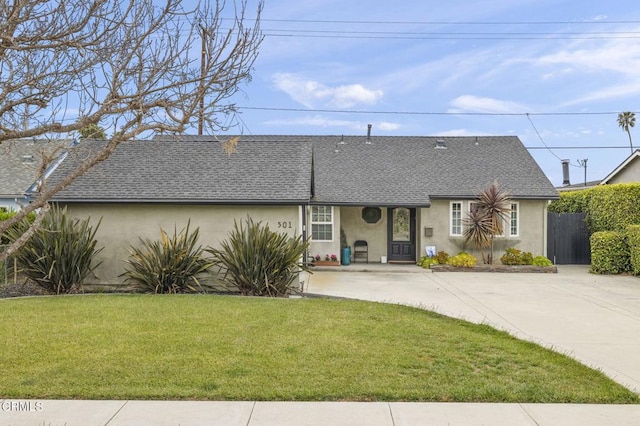 ranch-style home featuring stucco siding, fence, a shingled roof, concrete driveway, and a front lawn