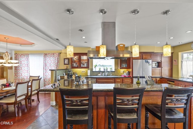 bar with a sink, stainless steel appliances, island range hood, visible vents, and backsplash