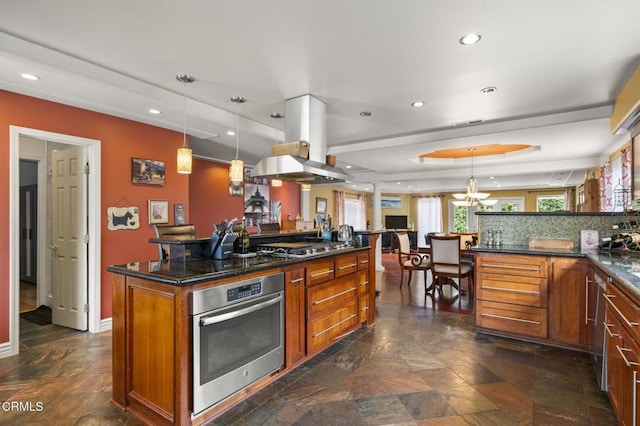 kitchen featuring stone finish flooring, brown cabinets, stainless steel appliances, and island exhaust hood