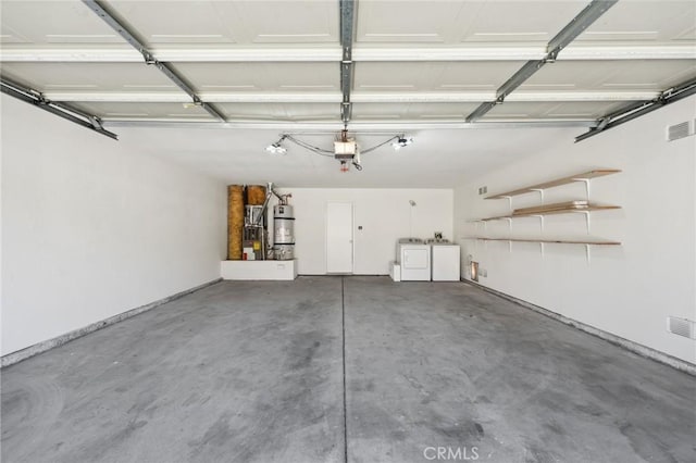 garage featuring washer and dryer, heating unit, water heater, visible vents, and a garage door opener