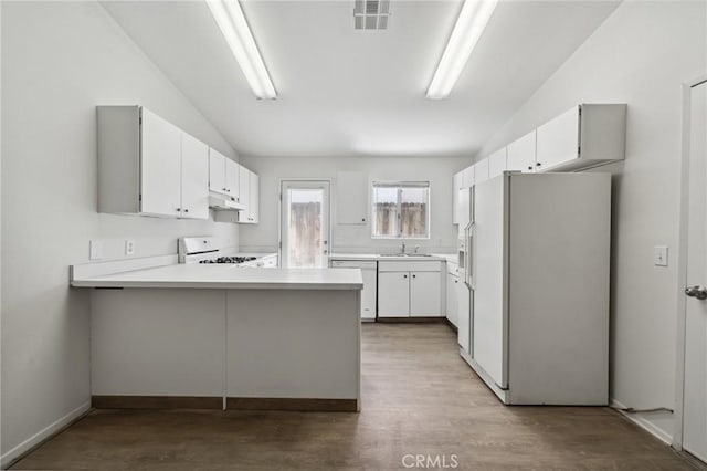kitchen with lofted ceiling, under cabinet range hood, white appliances, a peninsula, and light countertops