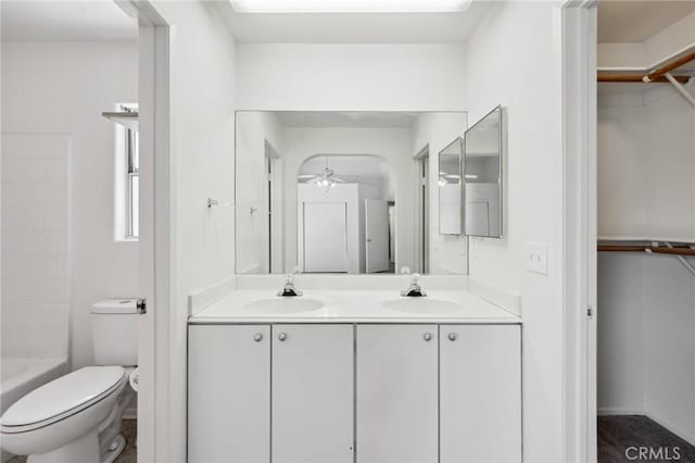 bathroom featuring a sink, double vanity, toilet, and a spacious closet