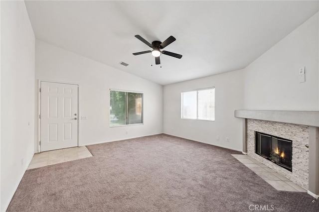 unfurnished living room featuring lofted ceiling, visible vents, a fireplace, carpet floors, and a ceiling fan