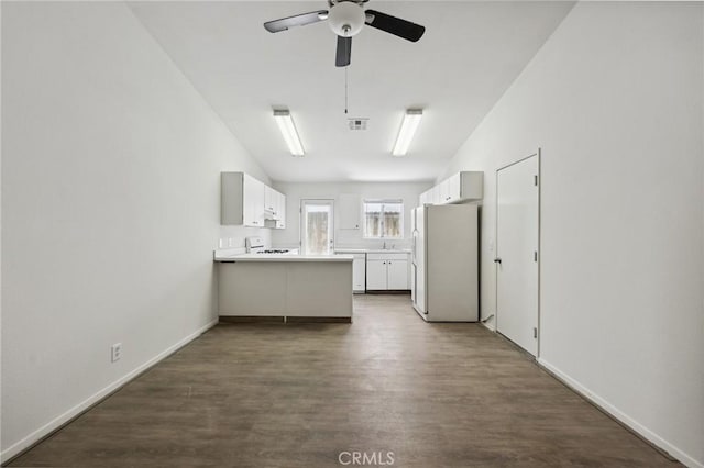 interior space with dark wood-type flooring, baseboards, a ceiling fan, and visible vents