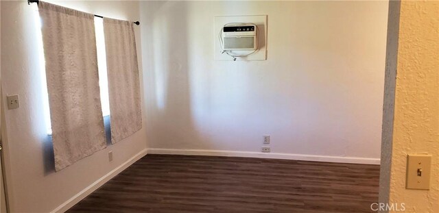 unfurnished room with baseboards and dark wood-style flooring