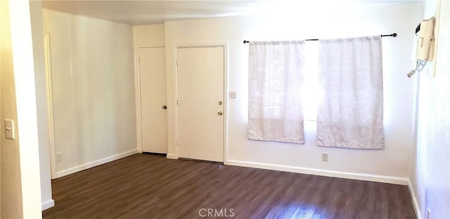 empty room featuring dark wood-type flooring and baseboards