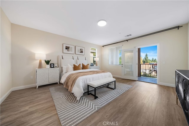 bedroom featuring baseboards, access to outside, light wood-style flooring, and visible vents