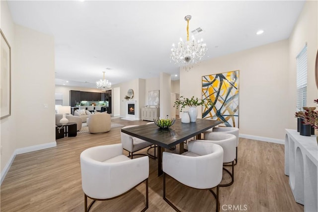 dining room with baseboards, light wood finished floors, a chandelier, and visible vents