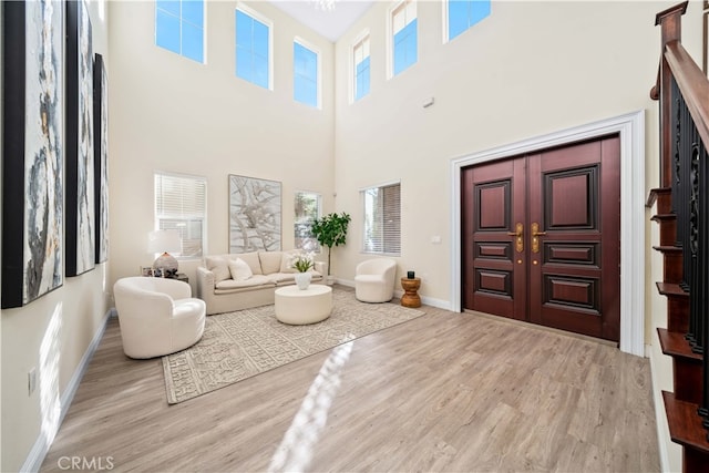 foyer featuring baseboards, a wealth of natural light, a high ceiling, and wood finished floors