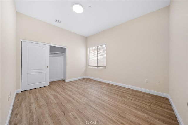 unfurnished bedroom with baseboards, light wood-type flooring, visible vents, and a closet