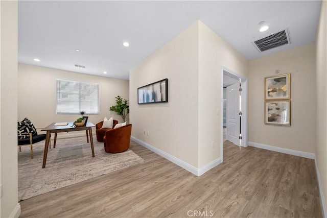 corridor with baseboards, visible vents, and light wood-style floors