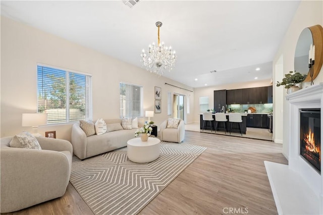living area featuring light wood-style floors, a healthy amount of sunlight, and a glass covered fireplace
