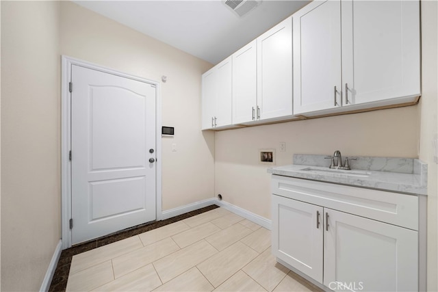 washroom with a sink, cabinet space, washer hookup, visible vents, and baseboards