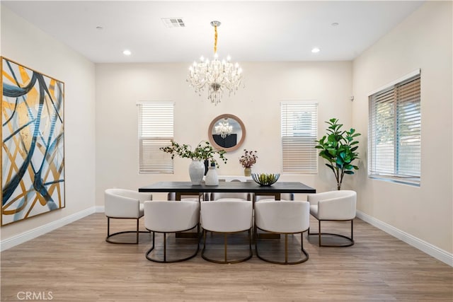 dining room featuring an inviting chandelier, light wood-style flooring, baseboards, and visible vents