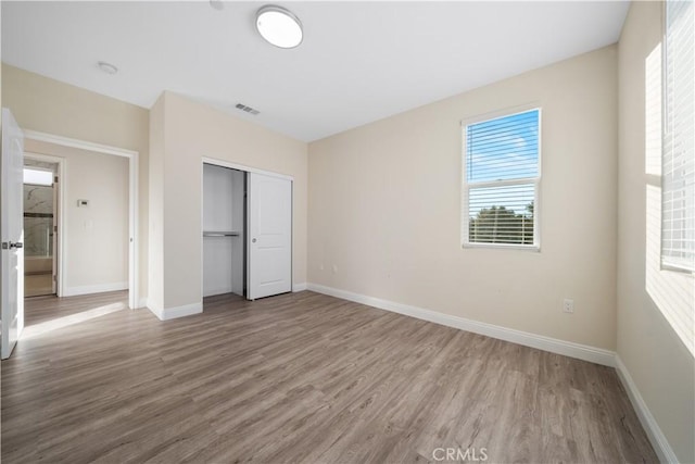 unfurnished bedroom with baseboards, visible vents, and wood finished floors