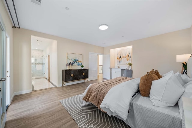 bedroom featuring baseboards, light wood finished floors, connected bathroom, and visible vents