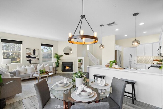 2852 N Santa Fe Pl, Orange, CA 92865 - dining space featuring a lit fireplace, a chandelier, visible vents, and recessed lighting