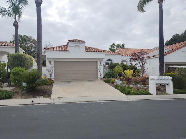 mediterranean / spanish-style house with concrete driveway, stucco siding, a tile roof, and a garage