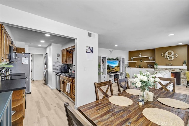 dining room featuring visible vents, recessed lighting, a fireplace, light wood finished floors, and stacked washing maching and dryer