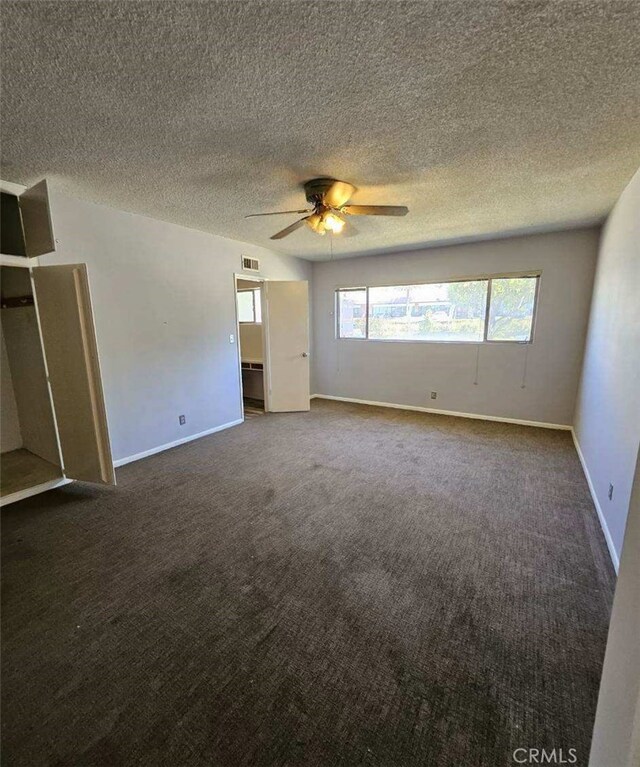 unfurnished bedroom featuring carpet, a textured ceiling, visible vents, baseboards, and ceiling fan