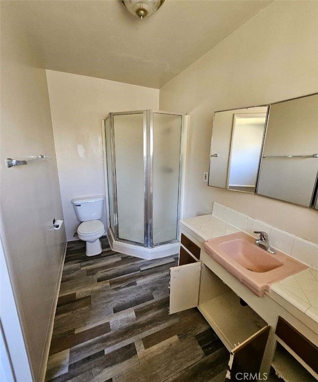 bathroom with a stall shower, vanity, toilet, and wood finished floors