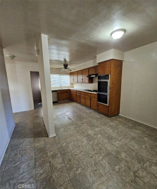 kitchen with stainless steel dishwasher, brown cabinetry, light countertops, and baseboards