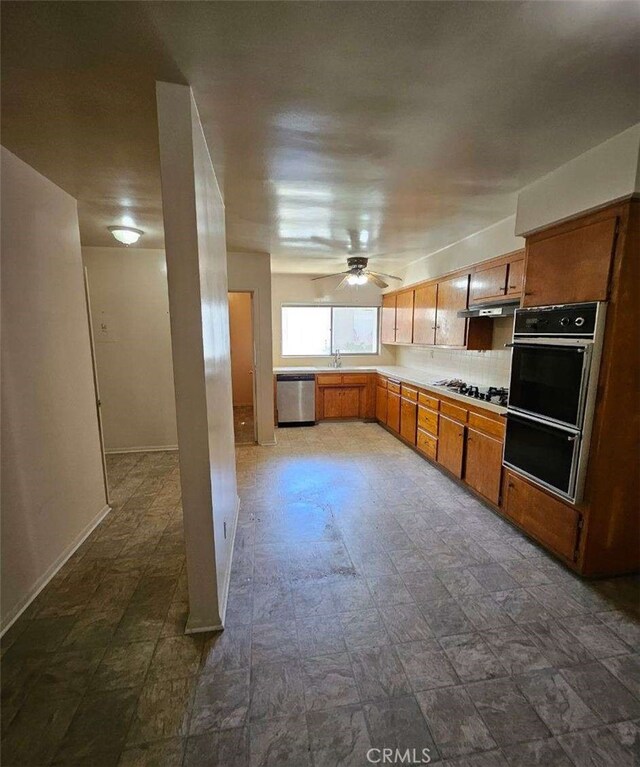 kitchen with light countertops, brown cabinetry, dobule oven black, ceiling fan, and dishwasher