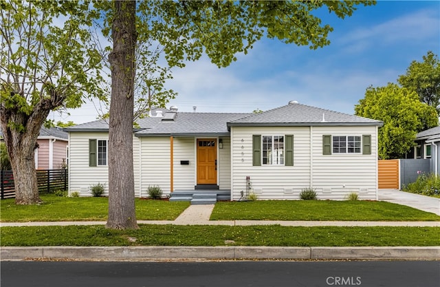 view of front of home featuring fence, a shingled roof, and a front lawn