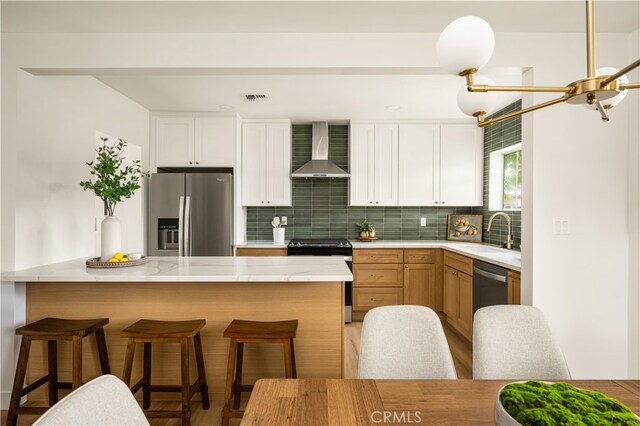 6655 Balcom Ave, Reseda, CA 91335 - kitchen featuring a sink, stainless steel appliances, a breakfast bar area, visible vents, and wall chimney exhaust hood