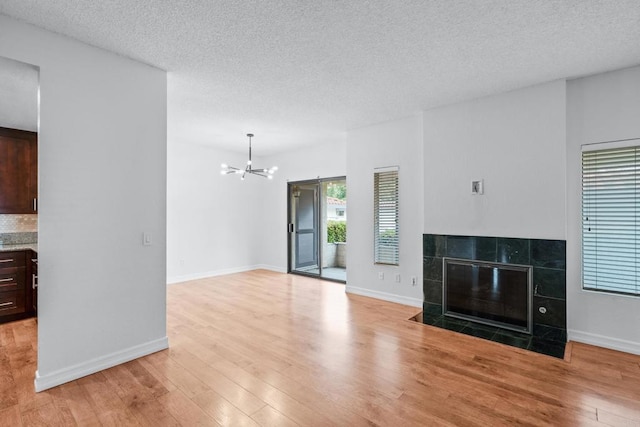 992 Lupine Hills Dr Unit 98, Vista, CA 92081 - unfurnished living room with a chandelier, light wood-type flooring, a tile fireplace, a textured ceiling, and baseboards